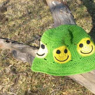 Bright green crochet bucket hat with yellow smile faces in small crochet squares