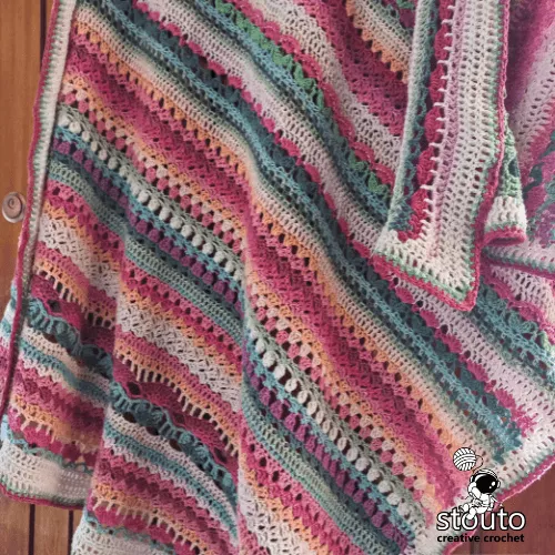 Pastel crochet blanket pattern worked as a lightweight floral sampler throw