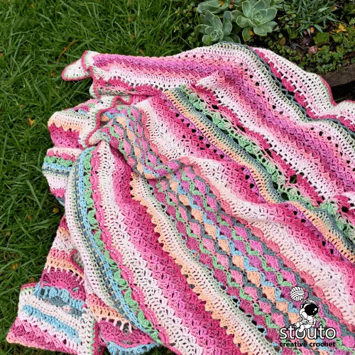 Pastel crochet blanket pattern worked as a lightweight floral sampler throw